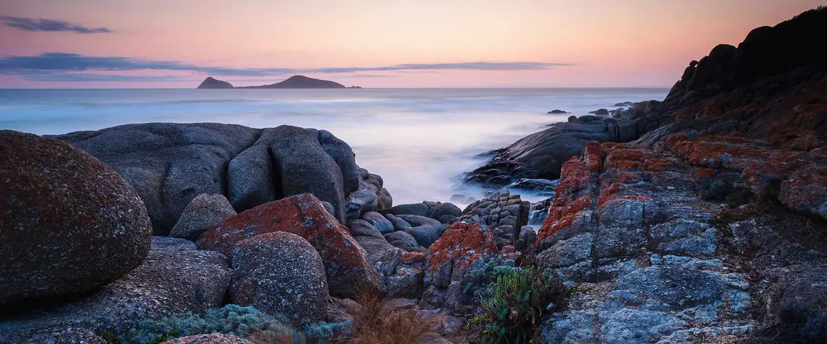 Lichen-covered granite rocks on the Prom coast at dusk