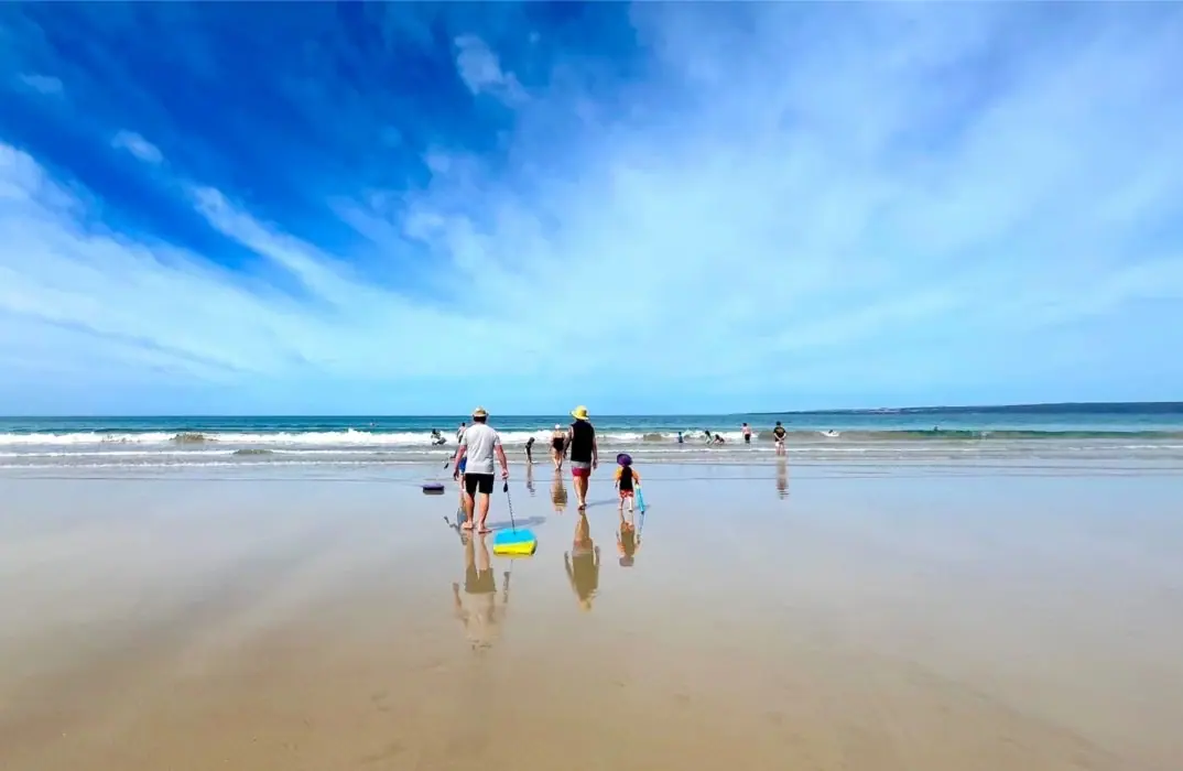 Families on the wide, shallow beach at Sandy Point at low tide
